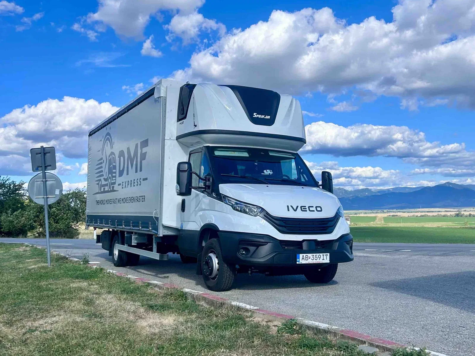DMF Express Iveco Daily 7.2 t curtain-side truck parked by the road with mountains in the background